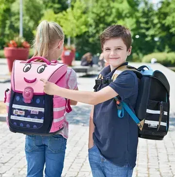 Schulrucksäcke in Verschiedenen Farben, Größen - Koffer.live Zwei Kinder mit Schulranzen, eines mit einem lächelnden Gesicht und das andere in Schwarz.