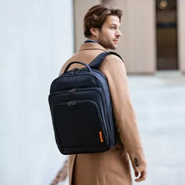 Rucksäcke in Verschiedenen Farben, Größen bei Koffer.live Junger Mann in einem beigen Mantel trägt einen schwarzen Rucksack.